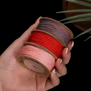 Detailopname van 1mm katoenen draadspoelen in rood, roze en meerkleurig voor DIY sieraden