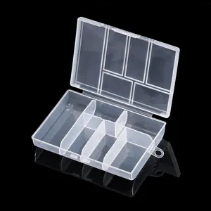 Macro view of a clear plastic storage box with multiple fixed compartments for jewelry.