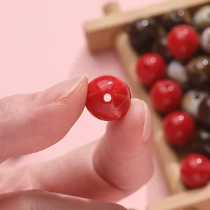 Close-up of a red round acrylic bead held by hand for DIY jewelry making and crafts