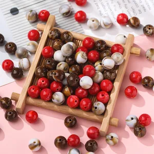Macro view of assorted red and marbled acrylic round beads on a bamboo tray.