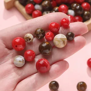 Hand holding mixed 8/10/12mm acrylic round beads for DIY jewelry making with marbled red and brown