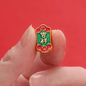 Close-up of a gold-toned Chinese style bead with auspicious engraving and red enamel.