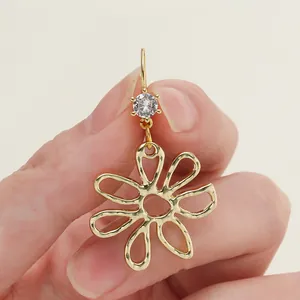 Close-up detail of 18k gold plated hollow flower earring drop with a sparkling zircon stone
