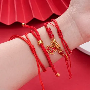 Close-up of red braided rope bracelets with a golden horse charm and red beads