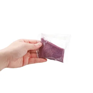 Hand holding fine purple laser glitter powder for resin and DIY crafts in packet