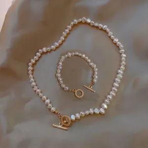 Détail de parure collier et bracelet en perles baroques avec fermoirs T dorés.