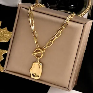 Vue détaillée d'un collier en acier doré avec fermoir OT et pendentif irrégulier