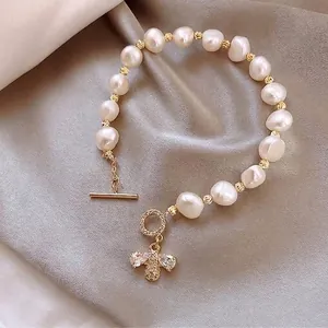 Gros plan du fermoir OT doré et du pendentif abeille en cristal sur un bracelet en perles