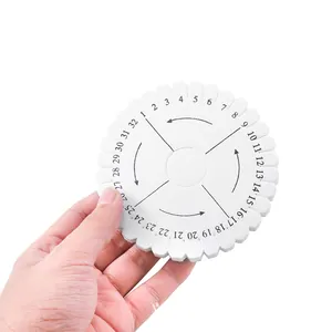 Main tenant un disque Kumihimo rond blanc pour le tissage DIY de bracelets et colliers.