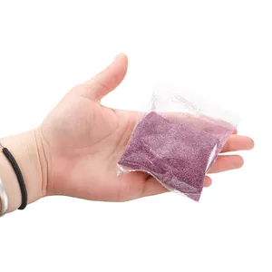 Detail view of fine purple laser glitter powder in a transparent bag held by a hand