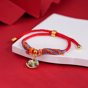 Macro view of a red braided cord bracelet featuring an intricate gold rocking horse charm