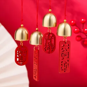 Primo piano di campanelli eolici dorati cinesi con placche in legno rosse incise.