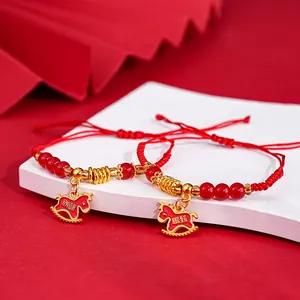Detailed macro shot of red string bracelets with golden rocking horse charms and beads