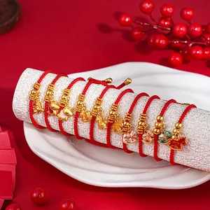 Close-up of red string bracelets with golden horse charms on a white display prop
