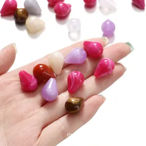 Gros plan détaillé de perles de gouttes en acrylique colorées à effet marbre tenues à la main.
