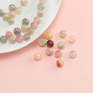Macro view of 10mm gilded glass beads with delicate floral patterns for DIY jewelry