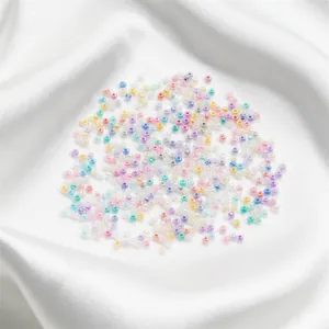 Dettaglio macro di perline di vetro colorate da 2 mm su tessuto di raso bianco