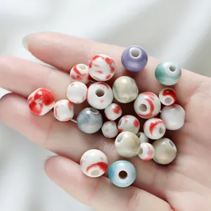 Detailed view of assorted ceramic beads held in hand for DIY jewelry making