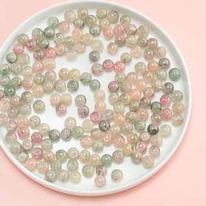 Close-up of 10mm flower-patterned glass beads in a white dish for DIY jewelry making