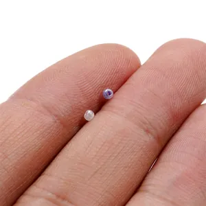 Primo piano di perline di vetro da 2 mm sulle dita per scala nella creazione di gioielli