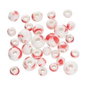 Close-up view of 6-12mm white ceramic beads with unique red splatter pattern for DIY crafts