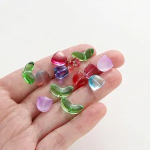Detailed macro view of colorful glass tulip petal and leaf beads held in hand for DIY jewelry.