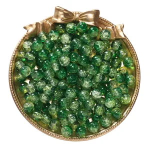 High-definition detail view of green crackle glass beads for DIY jewelry in a gold tray.