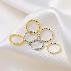 Set of twisted 18K and 14K gold plated jump rings for DIY jewelry making on white satin