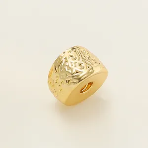 Macro detail of an 18k gold plated spacer bead featuring an intricate embossed vintage pattern