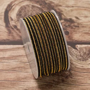 Macro detail of 2.5mm black and gold braided non-elastic cord on a plastic spool for DIY jewelry.