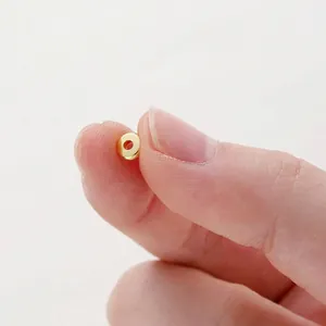Macro view of a tiny 14K gold-plated smooth wheel spacer bead for DIY jewelry