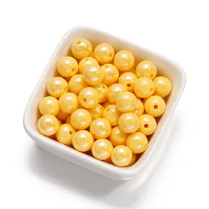 Gros plan de perles rondes en acrylique jaune de 10mm pour bijoux DIY dans un bol blanc