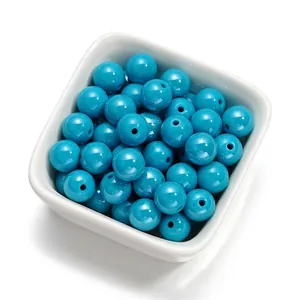 Gros plan de perles acryliques cyan de 10mm avec finition brillante dans un bol blanc