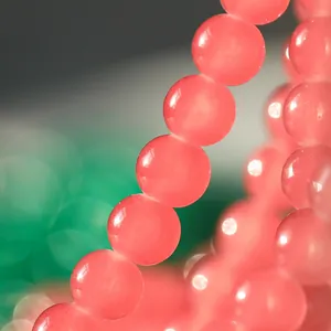 Primer plano de cuentas de vidrio translúcido rosa de 10 mm con textura de jade pulido.