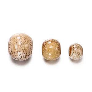 Detailed view of three ceramic beads with brown speckled texture in different sizes.
