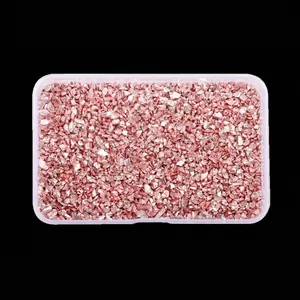 Detailed view of irregular rose gold metallic glass stones in a transparent storage box.