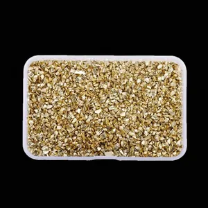 Close-up of golden irregular crushed glass stones for DIY nail art in a clear box