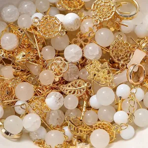 Detailansicht gemischter goldener Metallanhänger und weißer Glasperlen für DIY-Schmuck