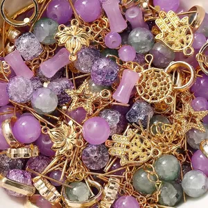 Detailansicht gemischter lila Glasperlen und goldener Metallanhänger für DIY-Schmuck