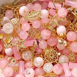 Detaillierte Makroaufnahme von rosa Glasperlen und goldenen Metallanhängern für DIY-Schmuck