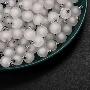Close-up view of frosted white acrylic round bead charms with silver loops