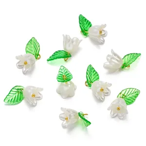 Macro shot of white acrylic lily-of-the-valley charms with green leaves for DIY crafts