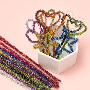 Colorful glitter pipe cleaners shaped into hearts and stars, held in a white ceramic cup