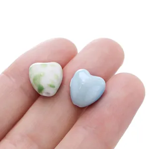 Macro detail of heart-shaped ceramic beads for DIY jewelry making on a finger