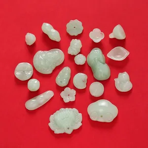 Various vintage green glass jade-like pendants for DIY jewelry making on red background