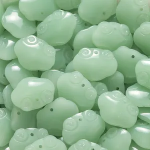 Macro view of cute light green frog-shaped glass beads for DIY jewelry making