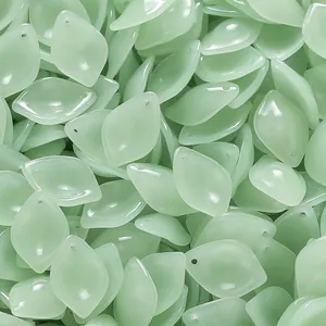 Close-up view of light green jade-like glass leaf pendants for DIY jewelry making