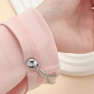 Detailansicht eines silbernen Magnetclips mit Kette an einem rosa Stoffärmel.