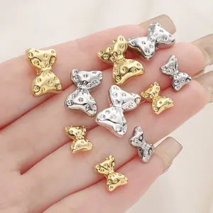 Vista dettagliata di perline a forma di fiocco in oro 18 carati e argento per gioielli fai da te