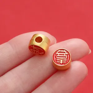 Détail de perles de transfert dorées avec émail rouge et caractères chinois pour création de bijoux